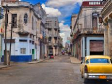  'Panoramic view of Havana street with crumbling buildings and old classic car'